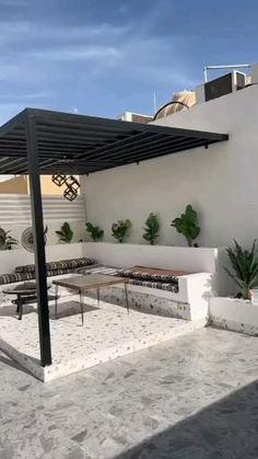 an outdoor living area with couches, tables and potted plants