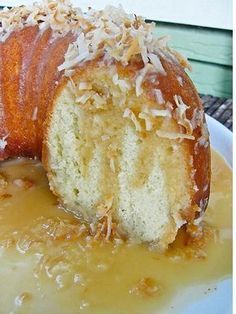 a bundt cake on a plate covered in caramel sauce and coconut flakes