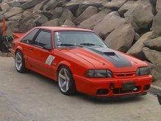 an orange car parked in front of some rocks