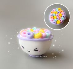 a bowl filled with lots of different colored beads next to a small object that looks like a cat