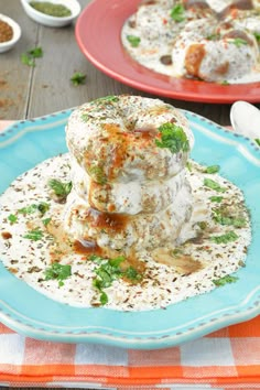 two plates filled with food sitting on top of a table next to bowls of sauce