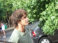 a young man standing next to a parked car