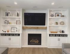 a living room with white built in shelves and a flat screen tv above the fireplace