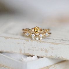 a yellow diamond ring sitting on top of a white box