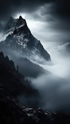 a mountain covered in fog under a cloudy sky