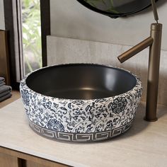 a black and white bowl sitting on top of a counter next to a faucet