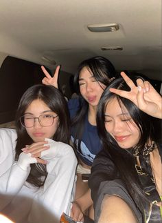 three young women sitting in the back of a car with their hands up and one pointing