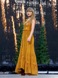 a woman in an orange dress is walking down the runway with her hand on her hip