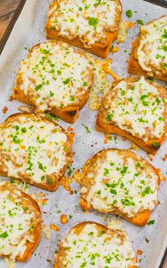 several pieces of bread topped with cheese and parmesan on a baking sheet lined with parchment paper