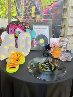 a table topped with vinyl records and neon colored letters on top of a black table cloth