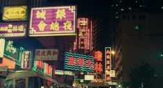 a busy city street at night with lots of neon signs on the side of buildings