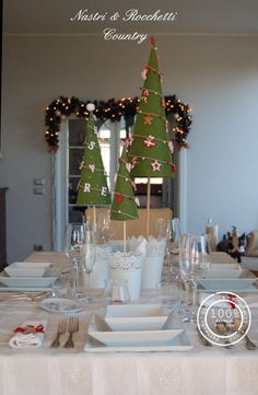 the table is set for christmas dinner with green trees on top and white dishes below