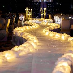 a long table covered in white cloths and lit candles