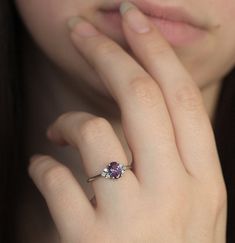 a close up of a person's hand with a ring on their finger and an amethyst