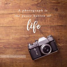 an old camera sitting on top of a wooden table next to a quote that reads, a photograph is the pause button of life