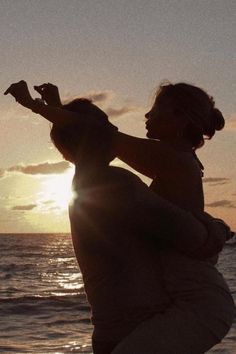 a woman holding a child on the beach at sunset