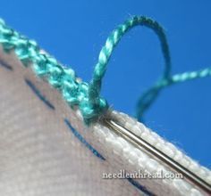 a close up of a piece of fabric with some knitting needles in front of it