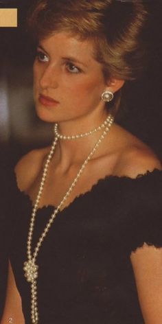 an old photo of a woman with pearls on her neck and shoulder, wearing a black dress