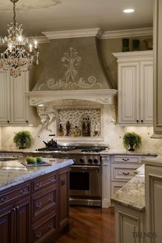 a kitchen with an oven, stove and counter tops in white painted cabinetry that has chandelier above it