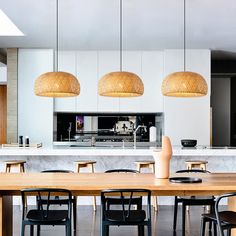 a dining room table with chairs and lights hanging from the ceiling