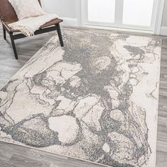 a white and gray rug in a living room with a chair next to the door