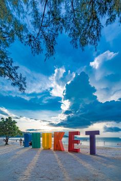 the word turke spelled out in colorful letters on a sandy beach under a cloudy blue sky