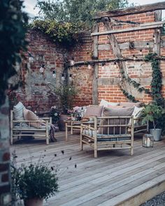 a wooden deck with couches and chairs on it next to an old brick building