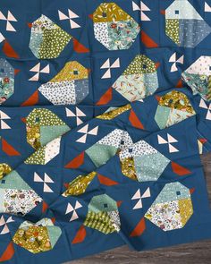 a blue quilt with many different shapes and sizes on the front, along with an orange one in the middle