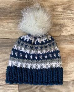 a blue and white knitted hat with a pom - pom on top