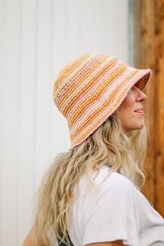 a woman with long blonde hair wearing a multicolored knitted beanie hat