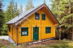 a yellow house with green shutters in the woods