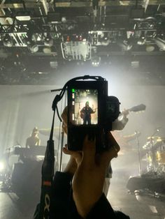 a person holding up a cell phone to take a photo in front of a stage