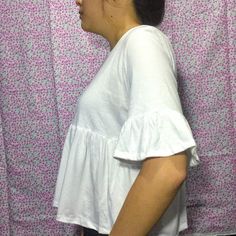 a woman standing in front of a wall with pink flowers on it's side