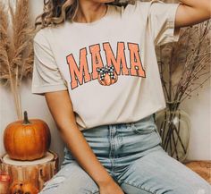 🍂 Celebrate Fall in Style: Get into the autumn spirit with our Pumpkin Fall Mama Shirt! Designed for all the trendy mamas out there, this shirt is a perfect blend of retro charm and modern style. It's the ideal piece to add a pop of fall flair to your wardrobe. 🎃 Retro Pumpkin Design: Featuring a vintage-inspired pumpkin graphic, this shirt exudes cozy, nostalgic vibes perfect for the season. The "Mama" script adds a personal touch, making it a stylish statement piece for all the fall-loving moms. 🍁 Versatile Fall Fashion: Available in a range of warm, autumnal colors, this shirt pairs effortlessly with your favorite jeans, leggings, or skirts. Whether you're heading to a pumpkin patch, enjoying a fall festival, or simply cozying up with a cup of coffee, this shirt is your go-to for cas Retro Graphic Print Tops For Fall, Retro Orange T-shirt For Fall, Trendy Short Sleeve Fall Shirt, Trendy Fall Short Sleeve Shirt, Retro Crew Neck Shirt For Fall, Trendy Graphic Print Shirt For Fall, Retro Cotton Tops For Fall, Trendy Fall Crew Neck Shirt, Trendy Crew Neck Shirt For Fall