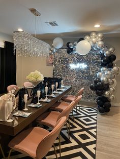 a dining room table set for a party with black, white and silver balloons