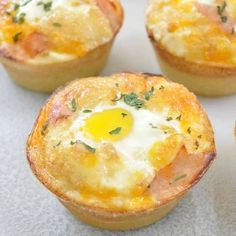 several small muffins with eggs in them on a white tableclothed surface