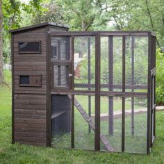 a chicken coop in the middle of a grassy area with trees and grass around it