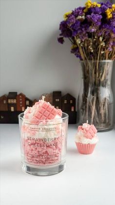 a cupcake shaped candle next to a vase filled with flowers