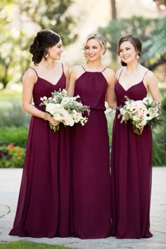 three bridesmaids in purple dresses are standing together and smiling at each other with their bouquets