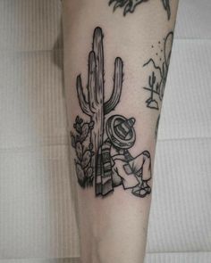 a black and white photo of a person with a cactus tattoo on their leg,