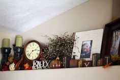 there is a clock and other decorations on the mantle in this living room, along with pictures