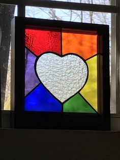 a stained glass window with a heart on it's side and trees in the background