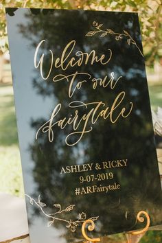 a welcome sign is displayed in front of a tree for guests to come home from their wedding