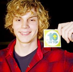 a young man with curly hair holding up a sticker