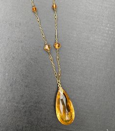 "A lovely Art Deco era 14K gold and citrine drop necklace. The citrine briolette drop is a sunny yellow color and measures an impressive 34 mm long by 17 mm wide by 11.4 mm deep. The many facets around the entire stone allows it to really shine. It has some natural inclusions as well as some minor surface abrasions as shown in the photos. The citrine is suspended from a delicate filigree necklace with citrine bead stations. Lovely open gold work on each gold panel. The clasp is stamped \"14K\" f Luxury Briolette Drop Necklace, Yellow Gold Briolette Gemstone Drop Necklace, Formal Yellow Gold Drop Necklace With Gemstone, Formal Amber Necklace In Fine Jewelry Style, Elegant Yellow Teardrop Pendant Jewelry, Formal Yellow Faceted Necklace, Formal Yellow Teardrop Pendant Jewelry, Yellow Teardrop Necklace For Formal Occasions, Yellow Teardrop Necklace For Formal Events