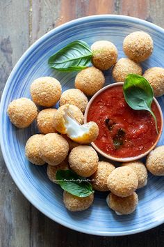 small appetizers on a blue plate with basil leaves and sauce in the middle