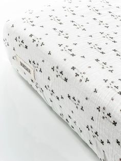 the mattress is made up with black crosses on it's white cover and bottom