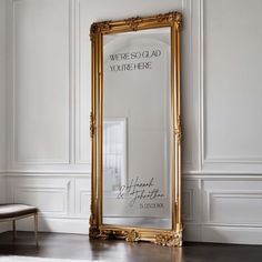 a large gold framed mirror sitting on top of a wooden floor next to a white wall