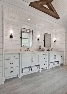 a large bathroom with two sinks and mirrors on the wall next to each other in white wood paneling