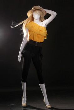 a mannequin wearing a yellow top and black pants with her hair blowing in the wind